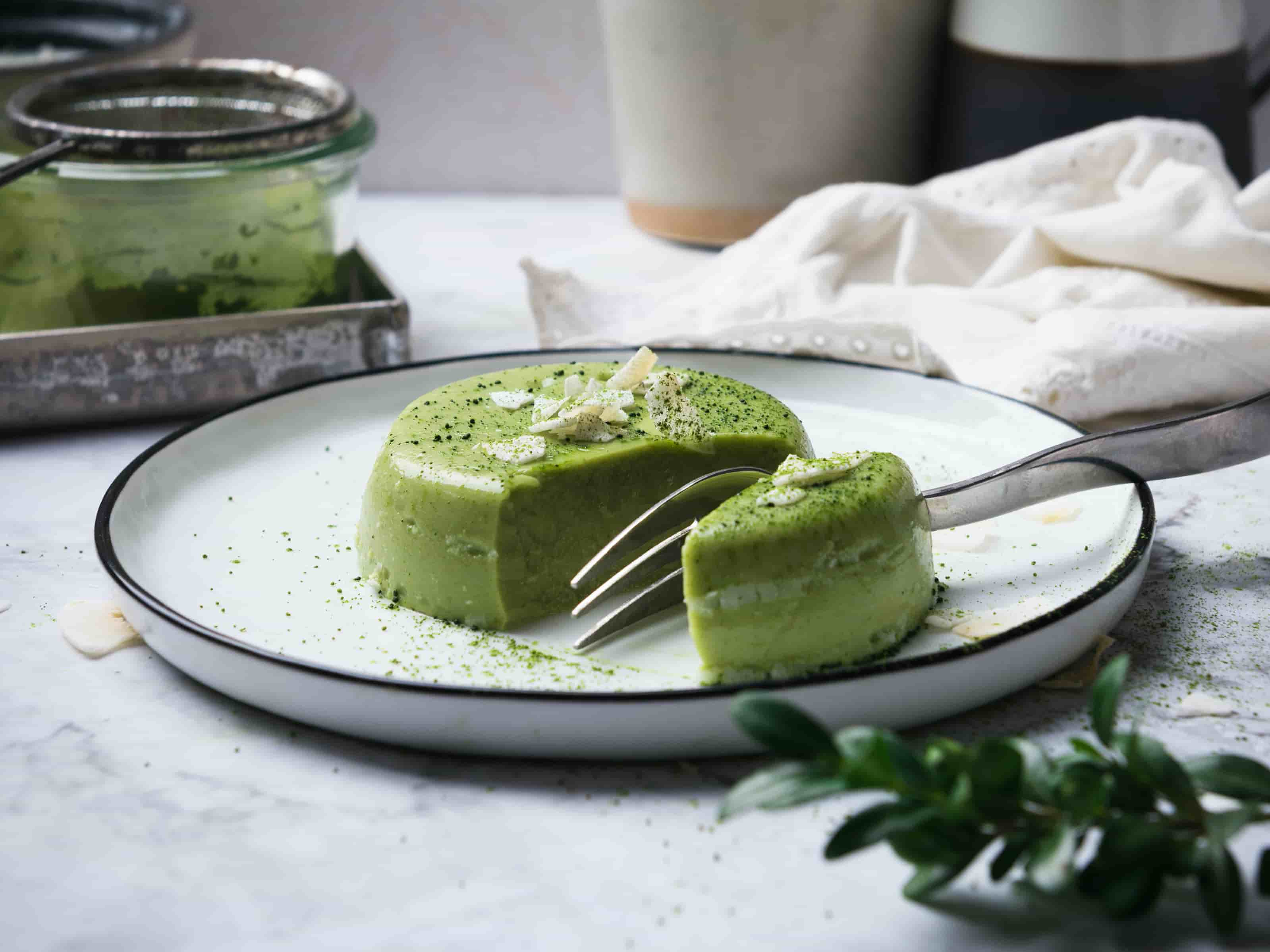 Gruene Panna Cotta mit Gabel halbiert, Kokosflocken darauf