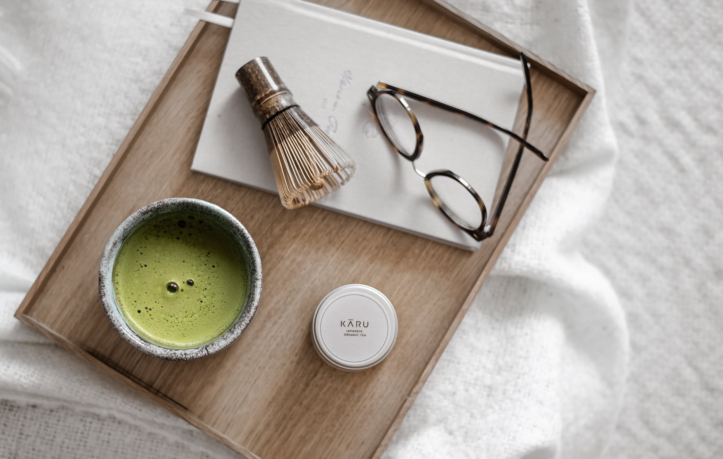 Matcha Set (Besen, Schale und Puvler) auf einen Tablett. In der Schale ist zubereiteter Matcha.