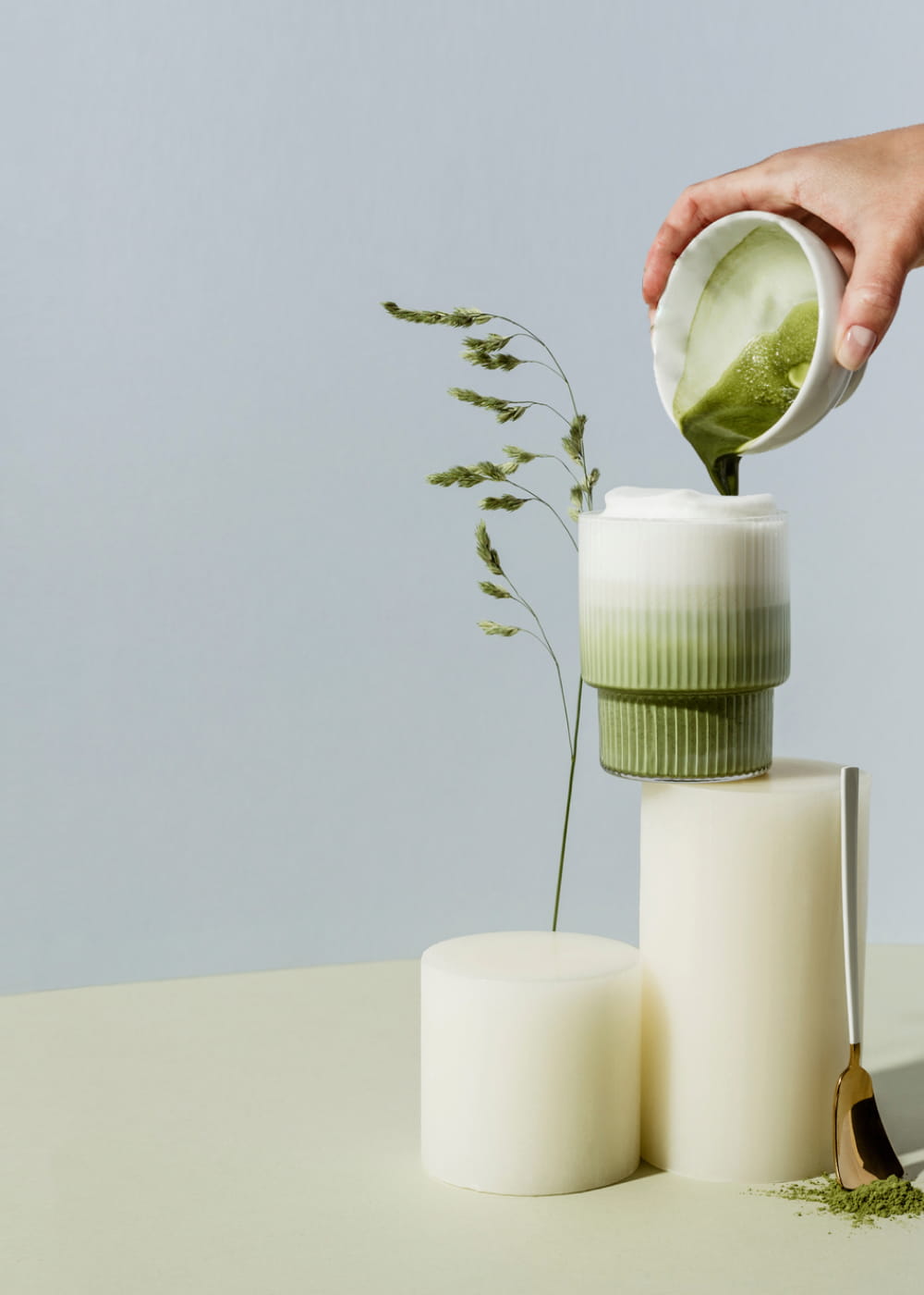 Matcha wird zur Zubereitung von Matcha Latte in ein Glas Milch gegossen