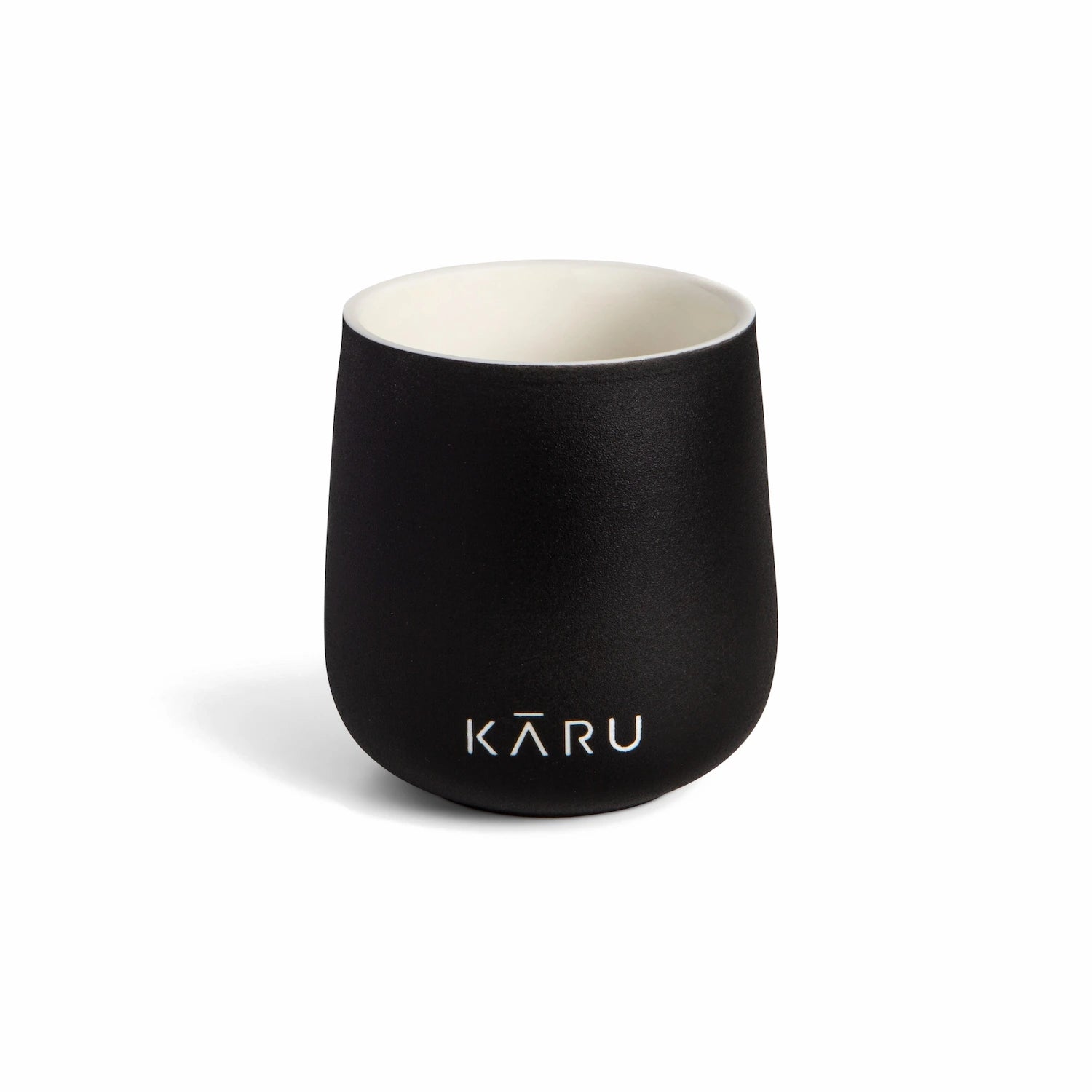 Eine schwarze Teetasse KĀRU aus Keramik (doppelwandig) mit dem Wort Matcha Kāru darauf.