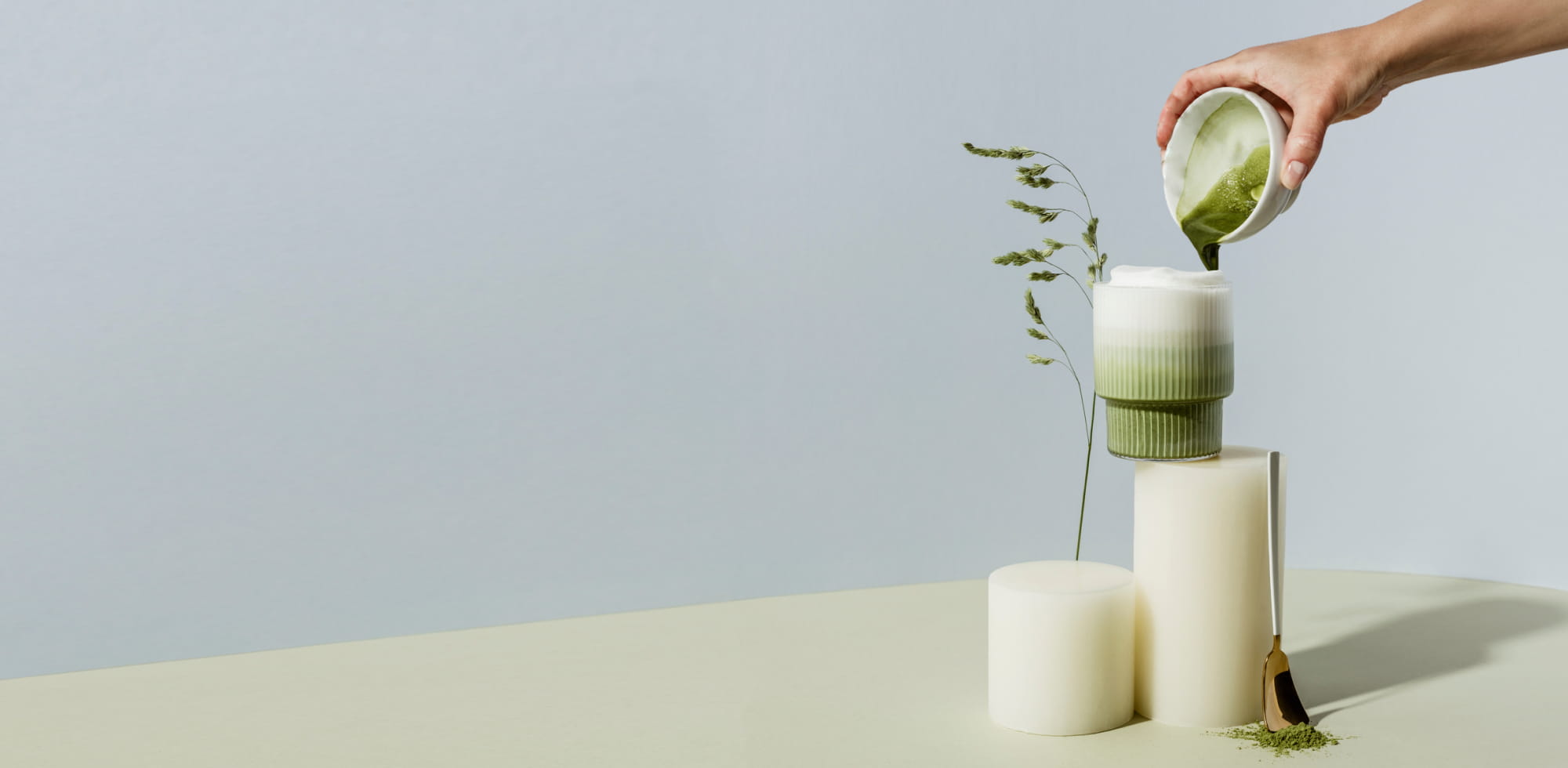 Matcha wird zur Zubereitung von Matcha Latte in ein Glas Milch gegossen