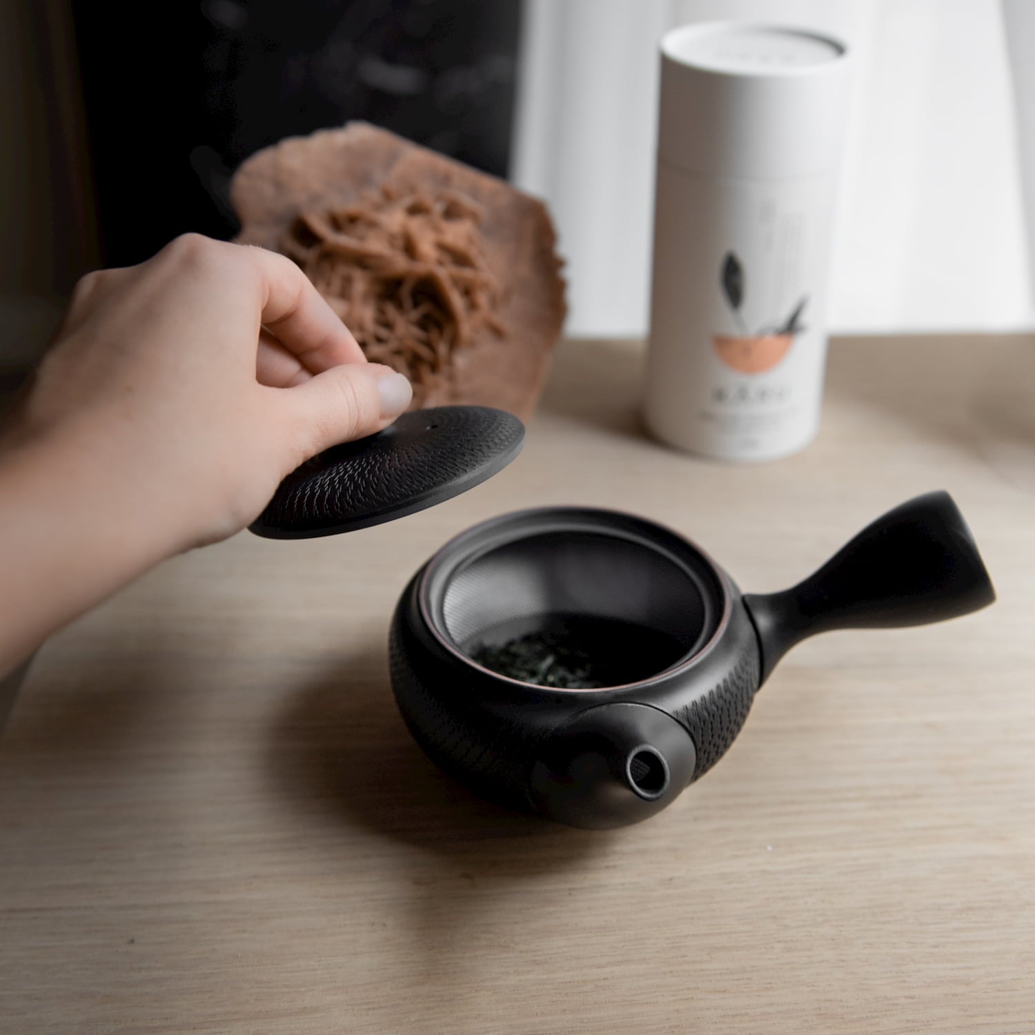Schwarze Japanische kleine Teekanne mit Hand